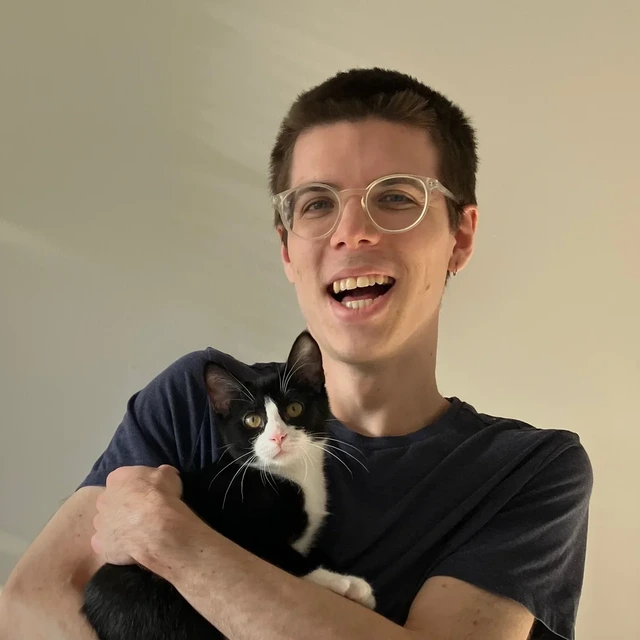 Chad smiling and holding his black-and-white cat Midna.
