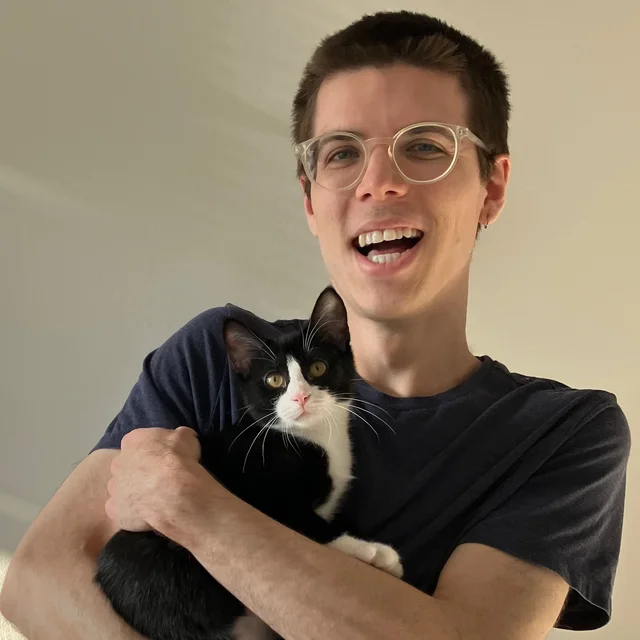 Chad smiling and holding his black-and-white cat Midna.