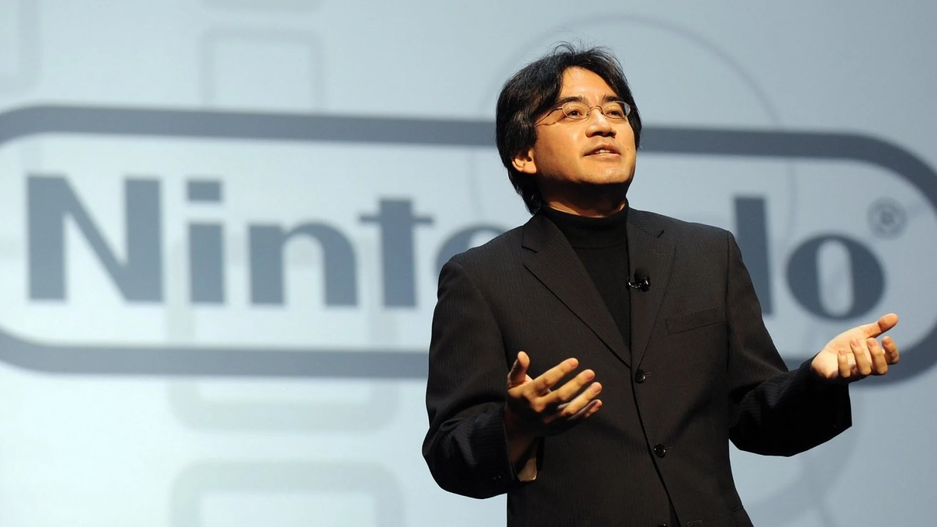 A picture of Satoru Iwata speaking in public at a live Nintendo event.